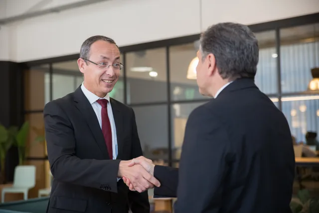 Two businessmen in suits shaking hands, symbolizing a successful business deal. Choix d'une agence pour les PME suisses : briefing, sélection et collaboration