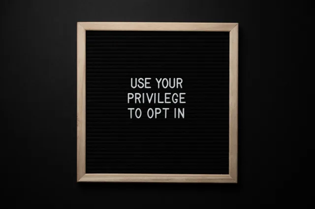 From above composition of contrast blackboard in wooden frame with white USE YOUR PRIVILEGE TO OPT IN title on black background. Marketing par e-mail en Suisse : listes, consentement et automatisation